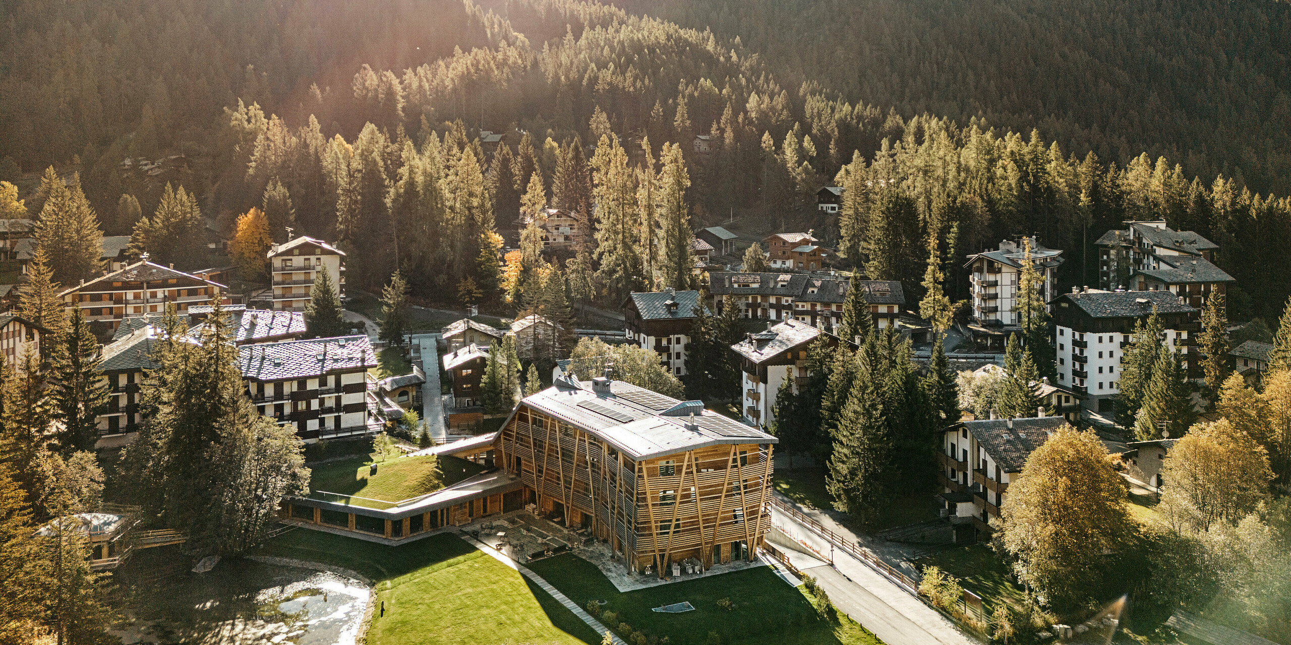 Drohnenaufnahme des Luxus-Öko-Hotels Au Charmant Petit Lac in Champluc mit einem PREFALZ-Dach in P.10 Steingrau und einer Holzfassade..
