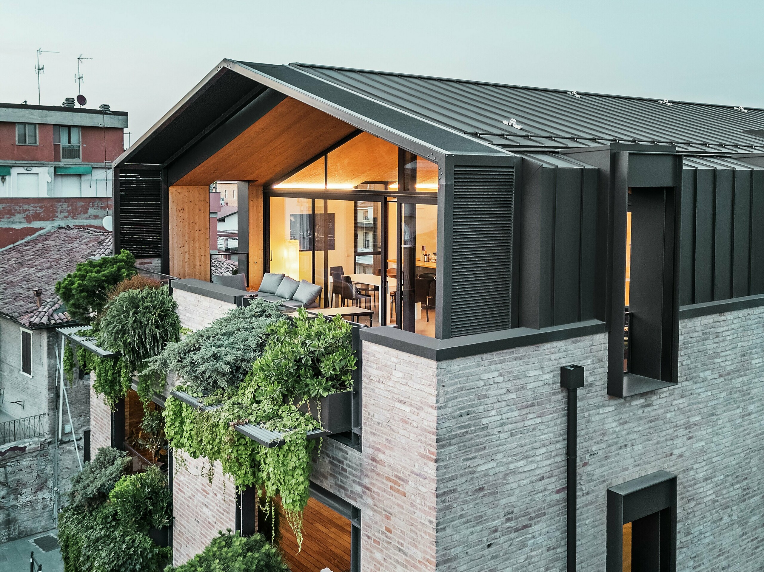 Modernes Wohnhaus in Italien mit PREFALZ Aluminiumdach in P.10 Nussbraun, großen Glasflächen, begrünter Fassade und Backsteinbauweise – gelungene Verbindung von Nachhaltigkeit und zeitgemäßer Architektur