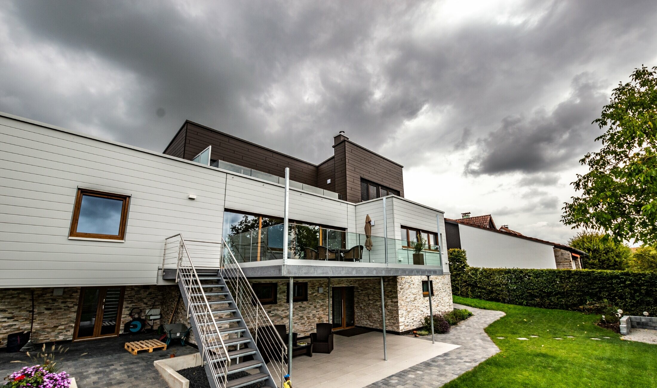 Casa residenziale con copertura piatta e facciata bianca e marrone con doghe PREFA posate orizzontalmente.