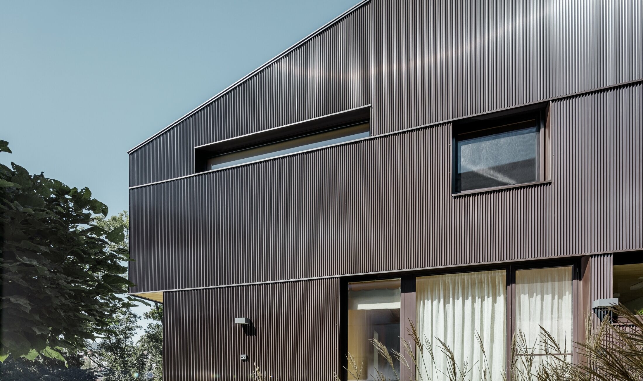 Moderna casa unifamiliare con rivestimento della facciata con profilo a zeta PREFA in marrone.