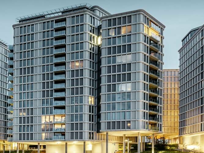 Viasta frontale dei "Belvedere Apartments" di sera. Il profilo estruso di PREFA è stato accostato a elementi in vetro e ceramica.
