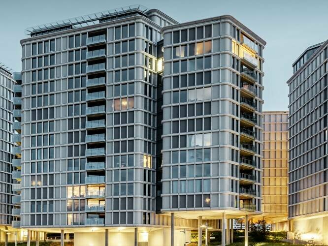 Viasta frontale dei "Belvedere Apartments" di sera. Il profilo estruso di PREFA è stato accostato a elementi in vetro e ceramica.