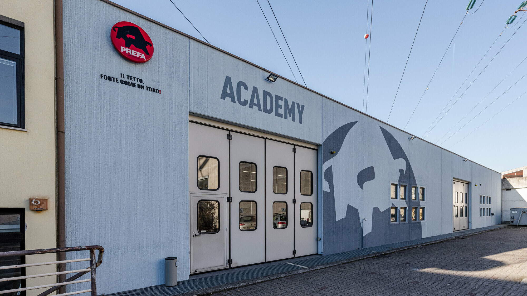 Fassade der PREFA Academy in Bozen mit dem Stier-Logo von PREFA in den Farben Grau und Weiß.