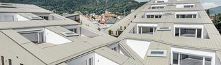 complesso residenziale di forma allungata a Graz con superfici di copertura piane e terrazze integrate e ampie vetrate con una copertura in Prefalz nel colore broncemetallic