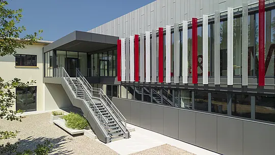 Foto parziale dell'ampliamento della scuola Arti e Mestieri di Suzzara con rivestimento Prefalz in patina grigio e Prefabond in grigio scuro.