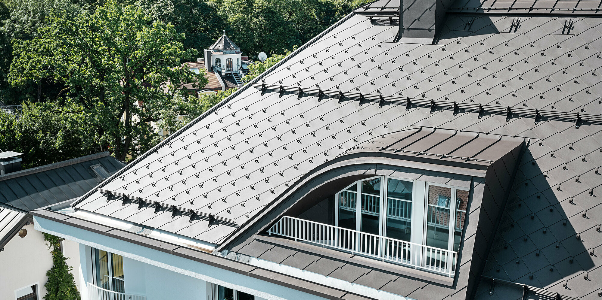 Casa plurifamiliare con scaglia PREFA 44 × 44 marrone con nasi fermaneve e sistema fermaneve
