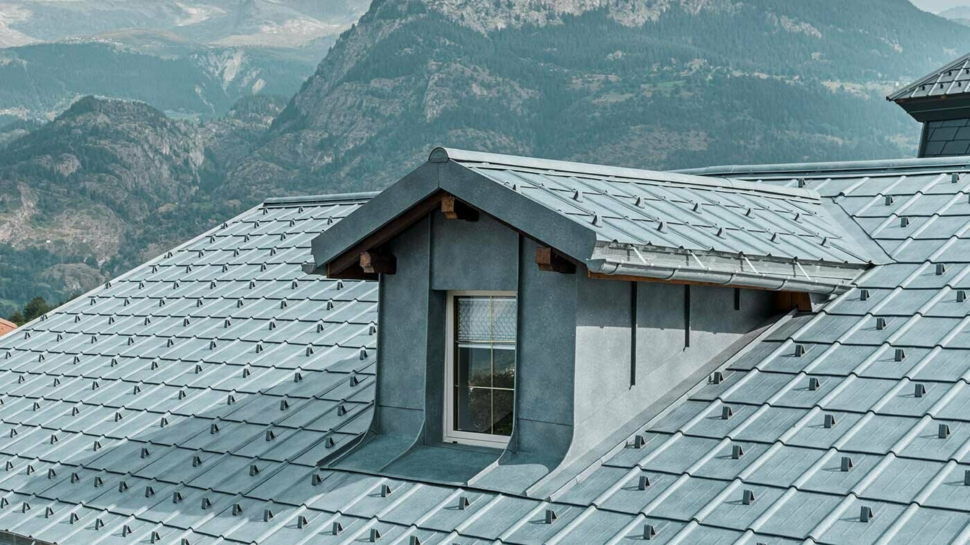 Partie d'un toit avec lucarne; Le toit était revêtu du panneau de toiture PREFA gris pierre, tandis que la lucarne servait de revêtement mural Prefalz gris pierre.