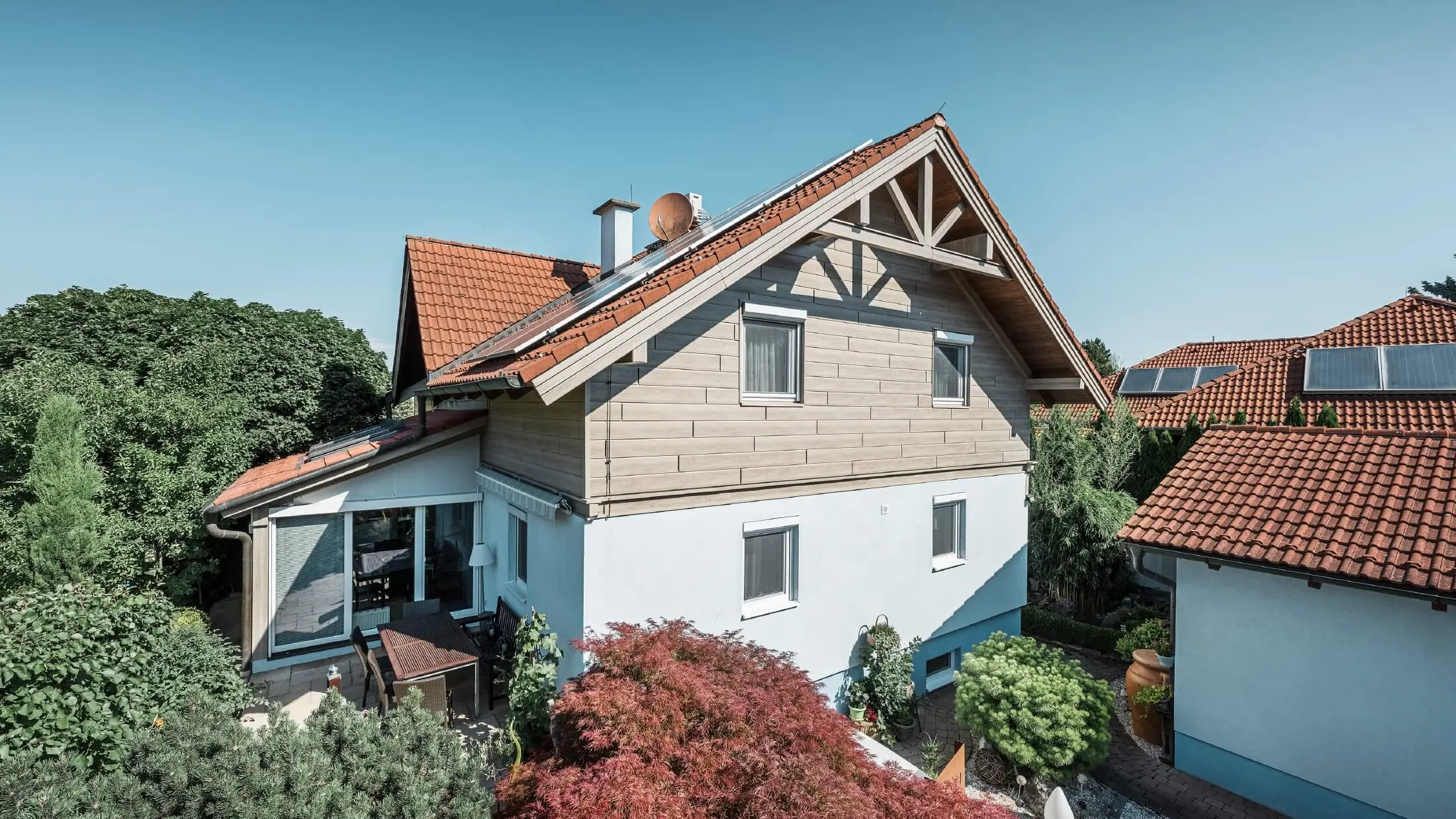 Facciata di una casa unifamiliare, rivestita al piano superiore con doghe effetto legno di color rovere grigio