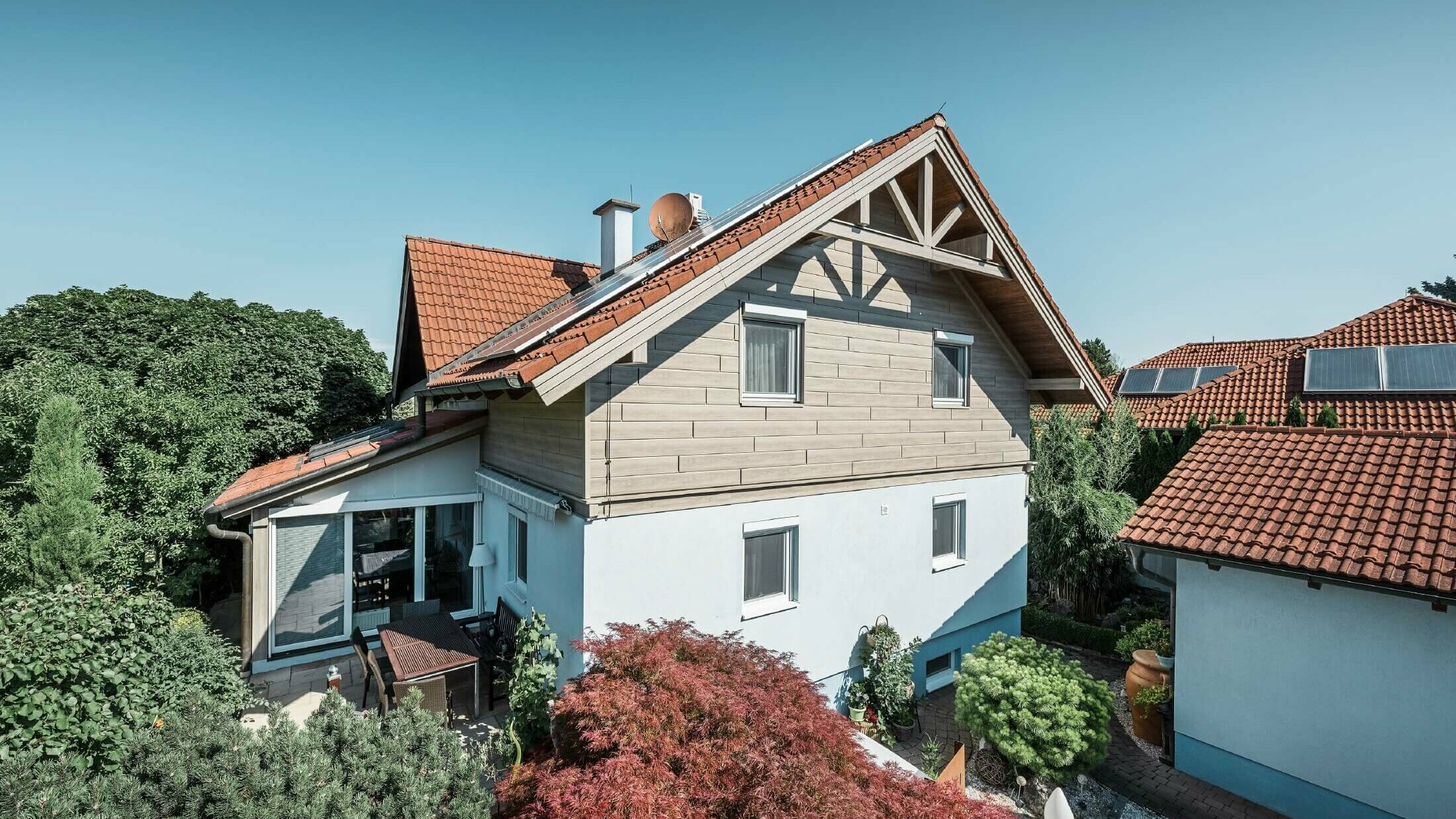 Facciata di una casa unifamiliare, rivestita al piano superiore con doghe effetto legno di color rovere grigio