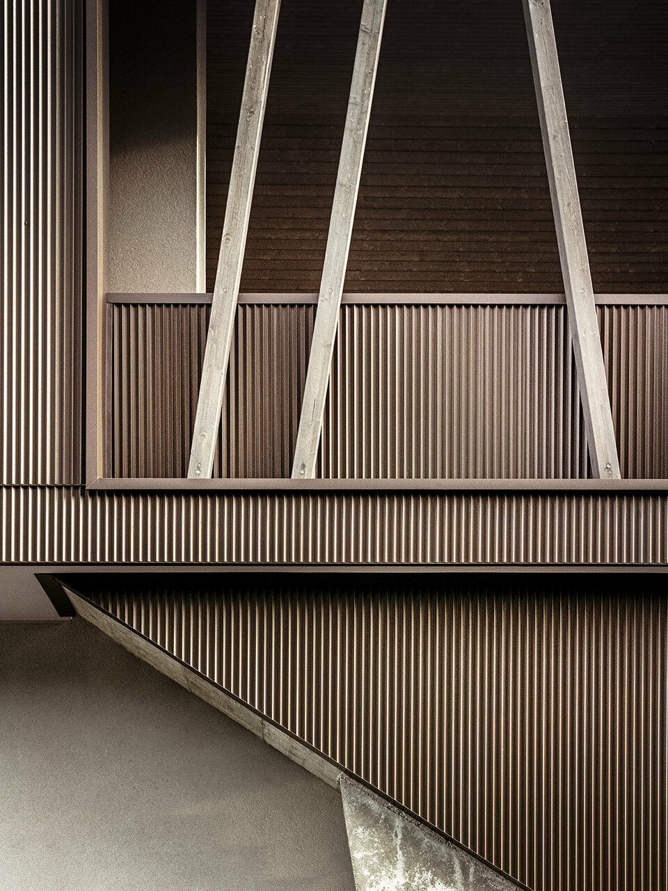 Eine Nahaufnahme der gezackten Aluminiumfassade mit den schräg gestellten Holzbalken der Villa 2B in Morbegno, saniert vom Architekten Massimo Mescia vom Büro altrostudio architetti.