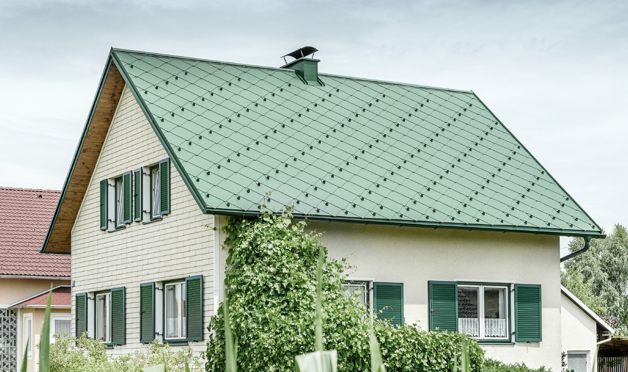 Casa unifamiliare classica con tetto a due falde con copertura in alluminio di colore verde muschio e  persiane verdi