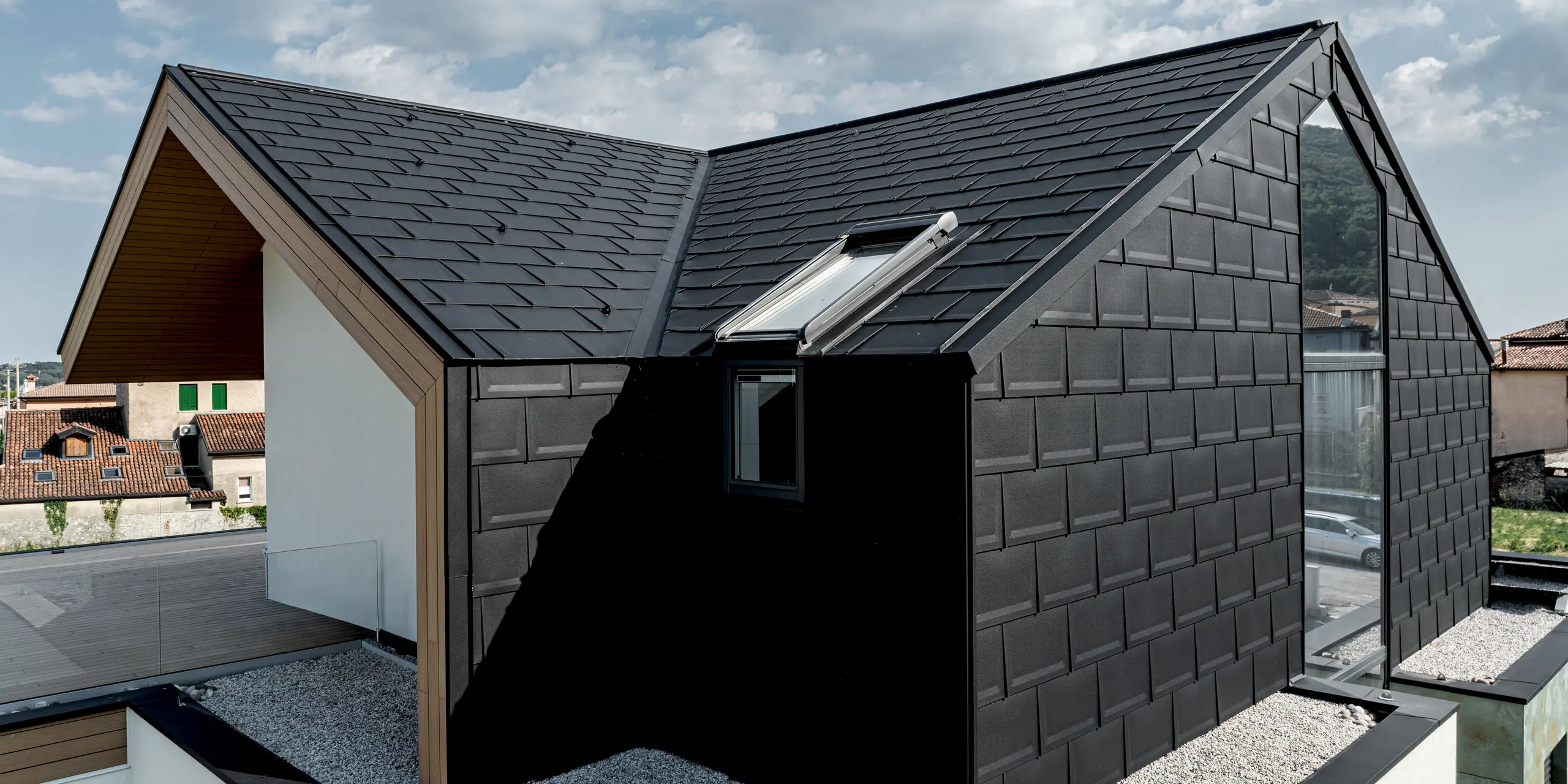 Detailaufnahme eines modernen Einfamilienhauses in Vicenza mit PREFA Dachplatte R.16 an Dach und Fassade in P.10 Schwarz. Die markante Aluminiumverkleidung unterstreicht die geometrische Architektur und sorgt für ein elegantes, einheitliches Erscheinungsbild. PREFA Lösungen überzeugen durch Langlebigkeit, geringes Gewicht und zuverlässigen Schutz vor wechselnden Witterungsbedingungen.