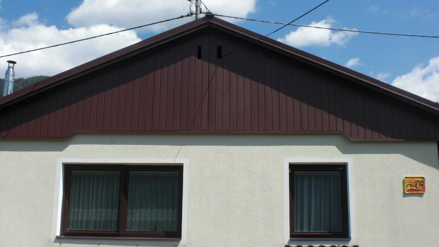 Ristrutturazione della facciata del timpano con doghe di rivestimento PREFA marroni, facciata verde chiaro