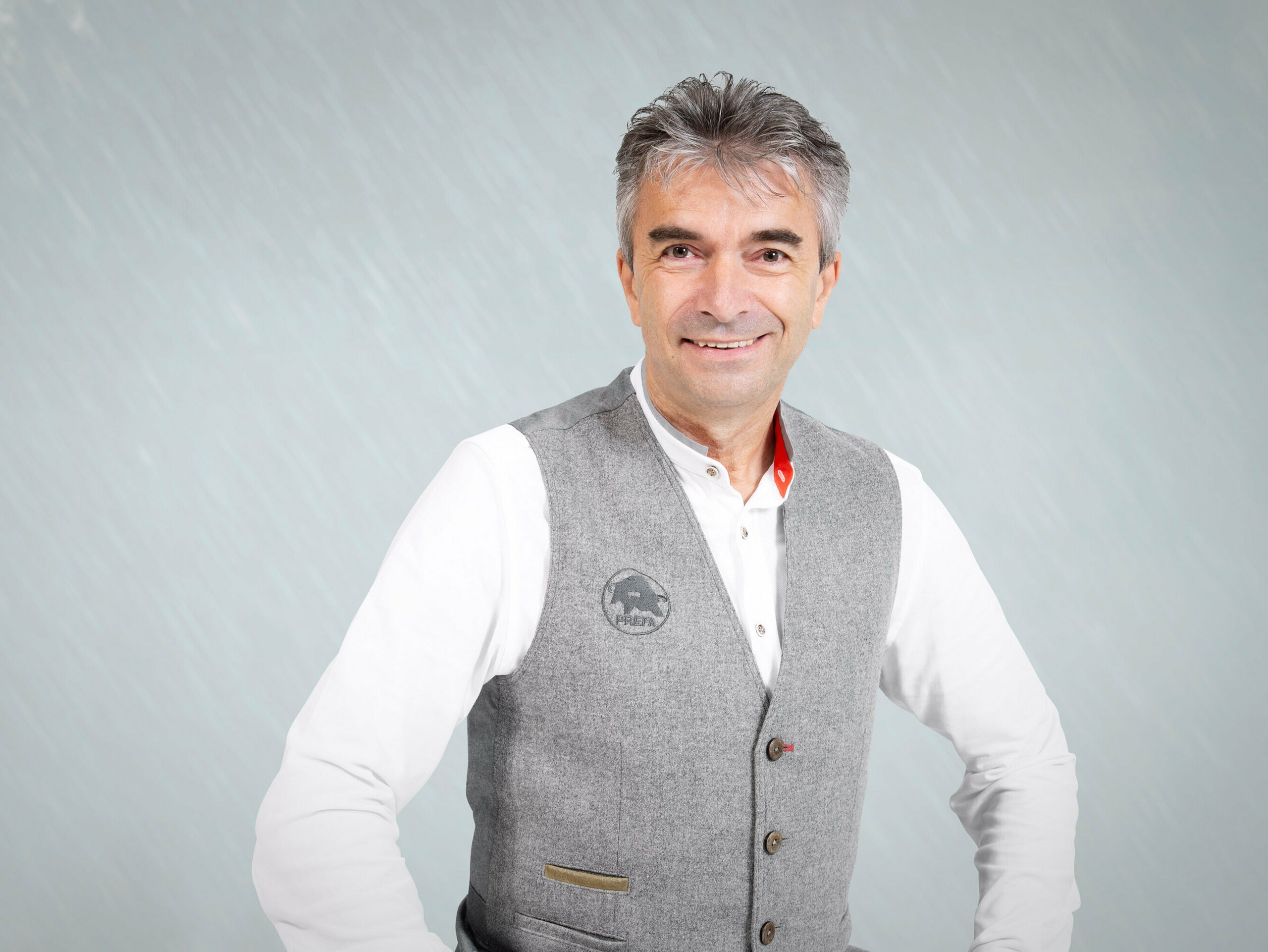 Porträt von Leo Höld, stellvertretender Leiter der PREFA Academy und tätig im Bereich der Produkttechnik. Leo trägt eine hellgraue Weste mit dem PREFA Logo und darunter ein weißes Hemd.