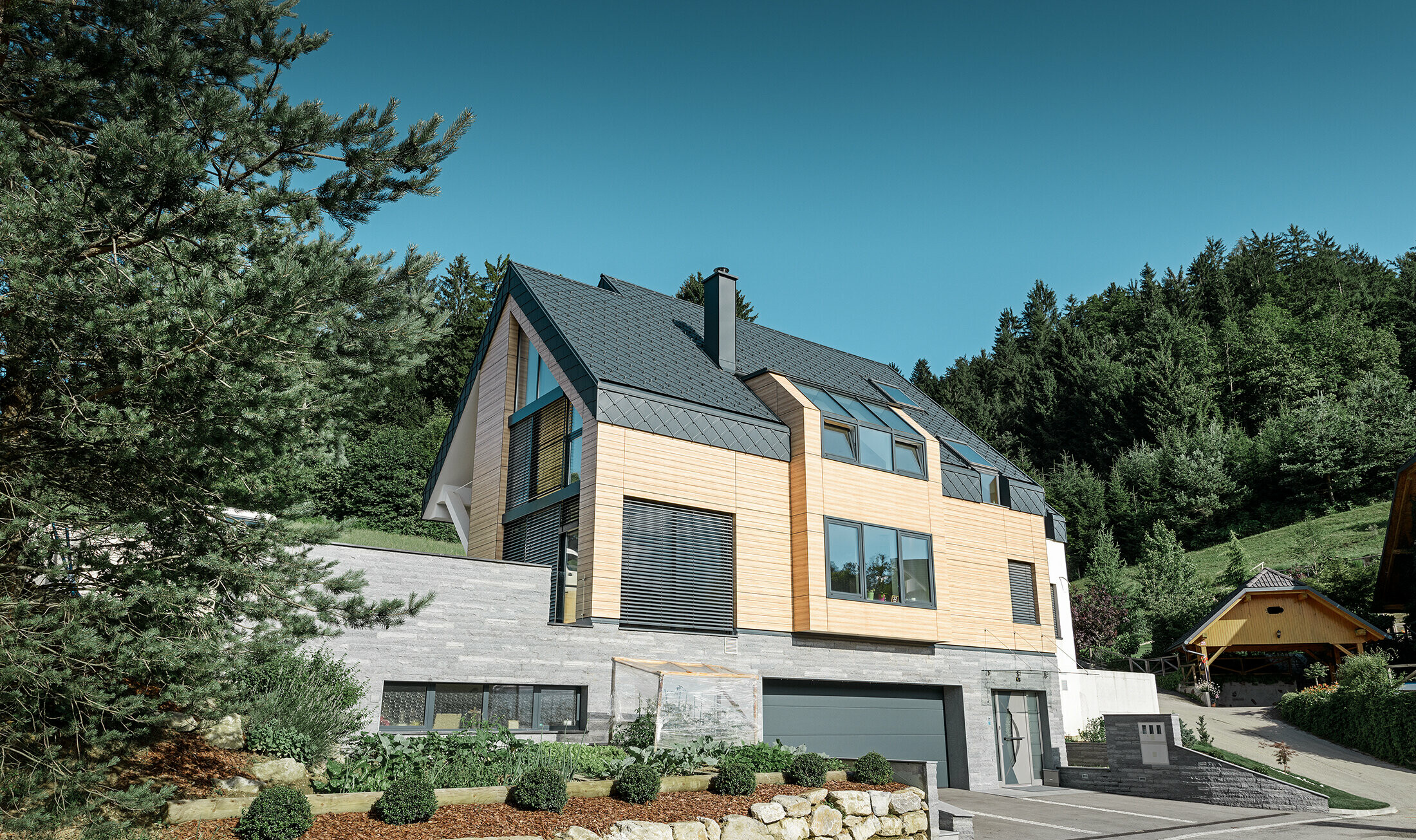 casa unifamiliare con tetto a due falde senza sporgenza del tetto con una facciata in finto legno e una copertura in alluminio in antracite
