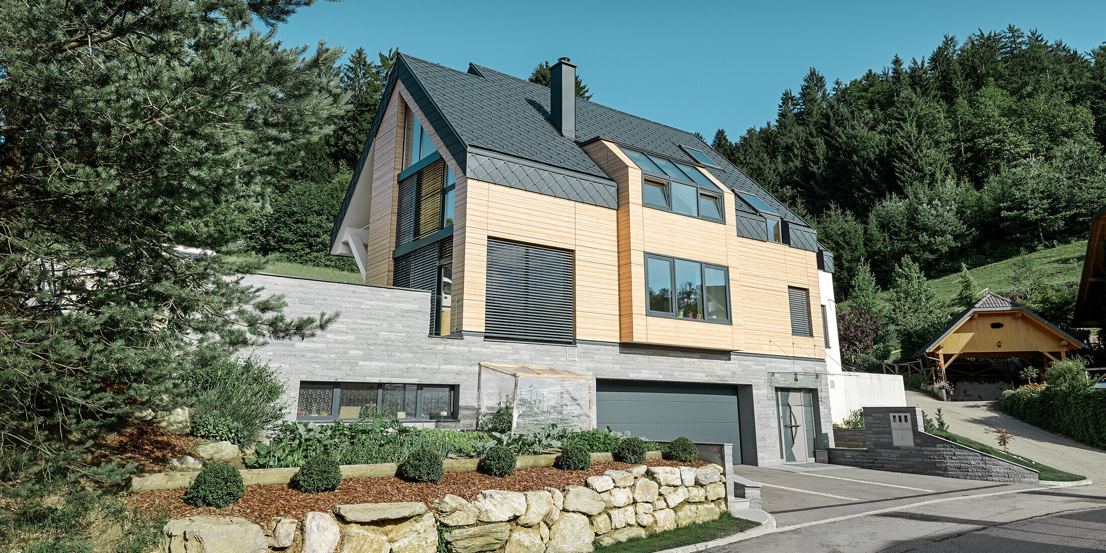 Einfamilienhaus mit Satteldach ohne Dachvorsprung mit einer Fassade in Holzoptik und einem Aluminiumdach in anthrazit