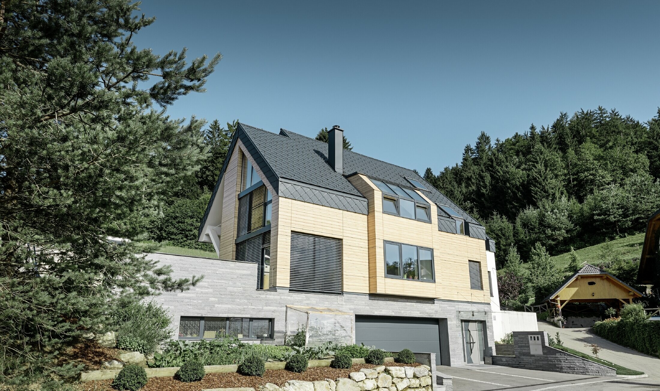 casa unifamiliare con tetto a due falde senza sporgenza del tetto con una facciata in finto legno e una copertura in alluminio in antracite
