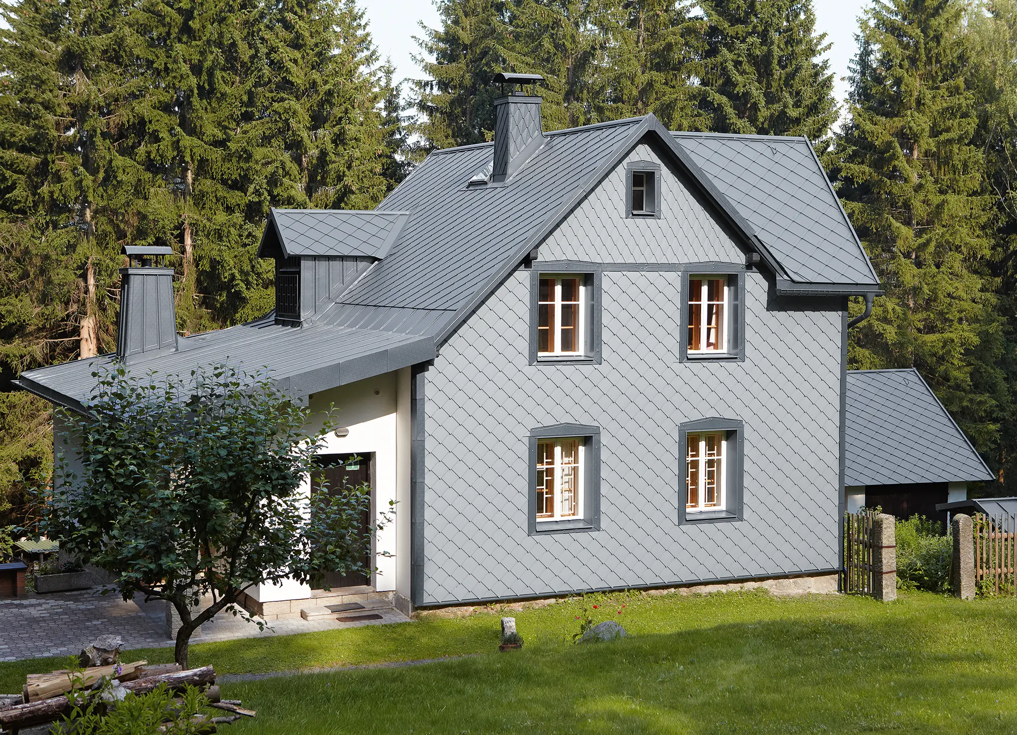 Einfamilienhaus in Waldlage mit witterungsbeständiger PREFA Aluminiumfassade in Hellgrau.
