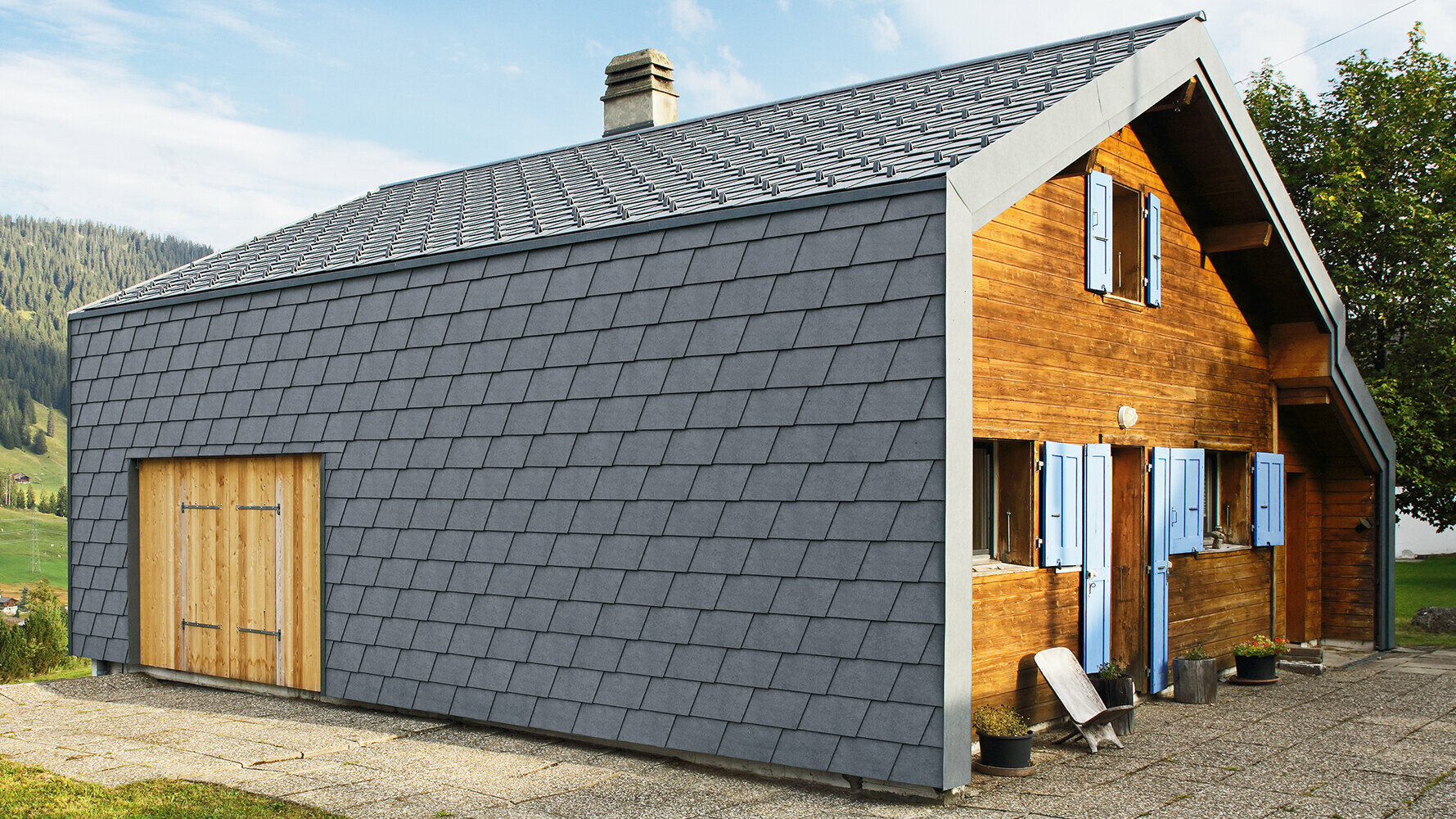 Modernes Einfamilienhaus verkleidet mit PREFA Wandschindeln in der Farbe P.10 Steingrau und Holzelementen.