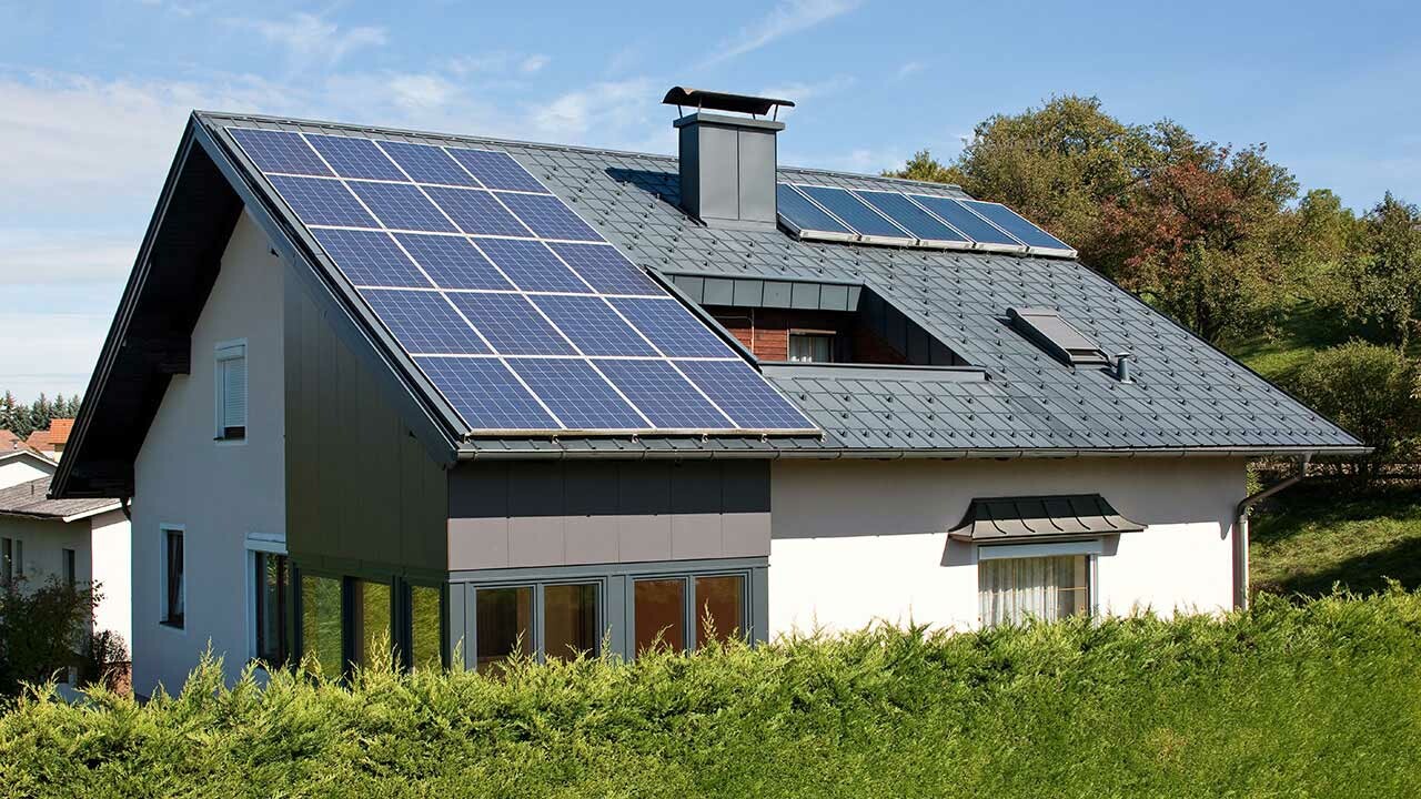 Casa unifamiliare rivestita con le tegole PREFA in grigio e un impianto solare con il sistema di montaggio PREFA