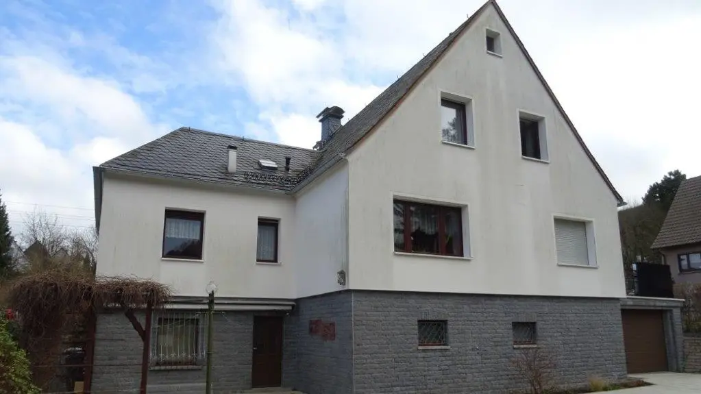 Wohnhaus mit alter Putzfassade in Weiß mit grauem Klinker.