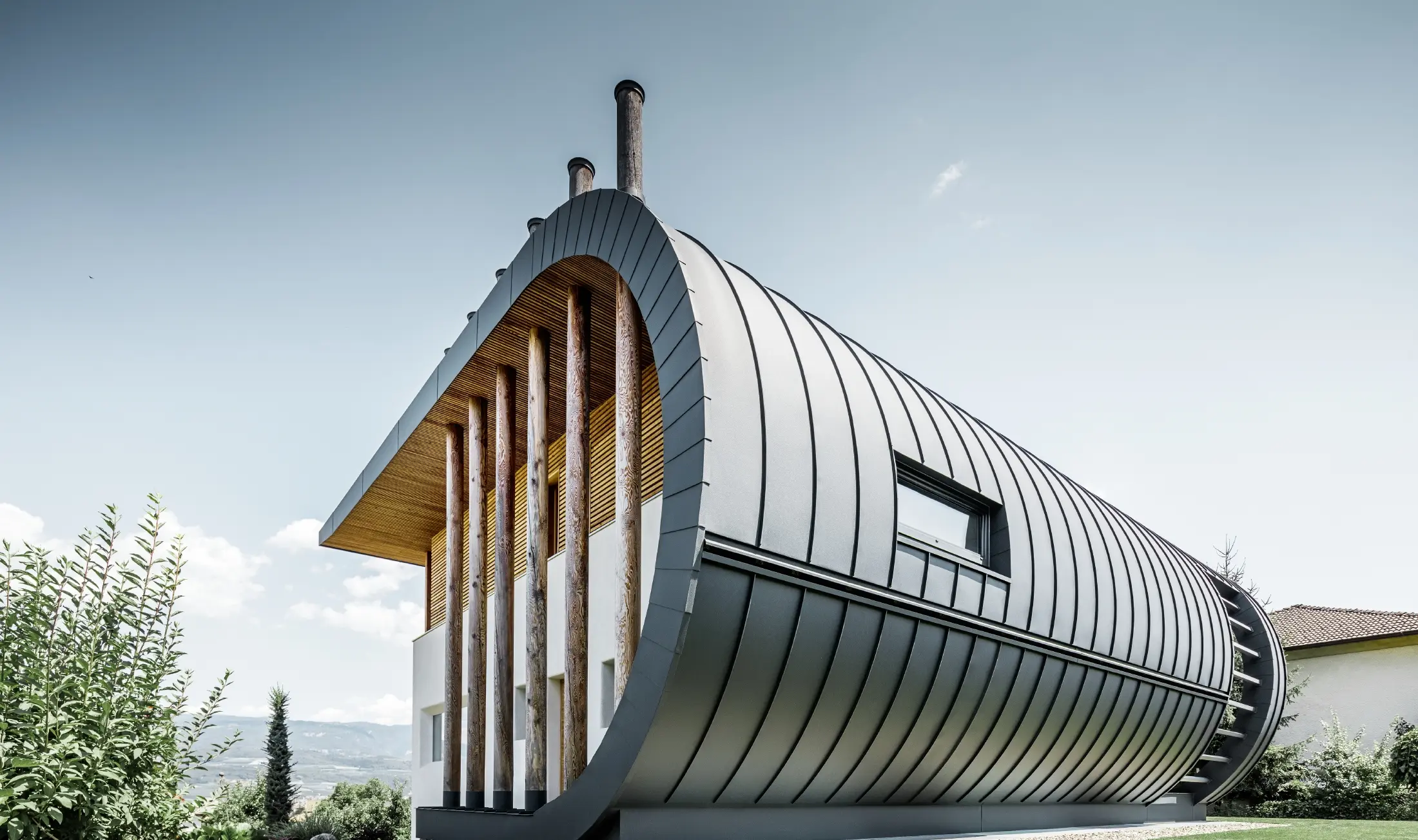 Facciata dalle linee curve nella casa unifamiliare Casa Giovannini rivestita con alluminio di PREFA - Prefalz in P.10 antracite.