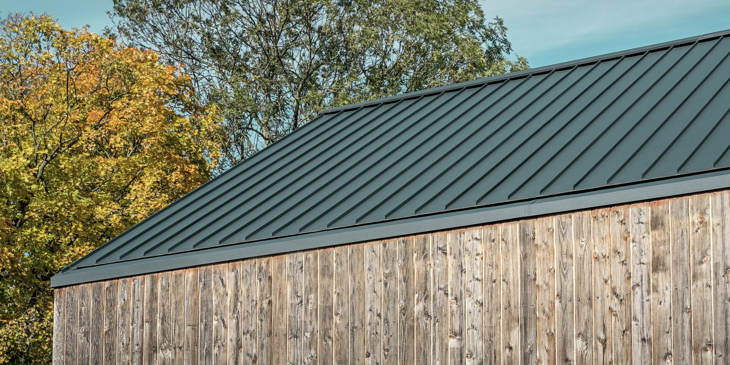 Modernes Satteldach mit PREFALZ Doppelstehfalz in P.10 Anthrazit. Das hochwertige Blechdach auf einem Wohnhaus mit der Fassade aus naturbelassenem Zedernholz schafft eine eindrucksvolle Optik. Das PREFA Dach ist langlebig, wetterbeständig und ästhetisch.