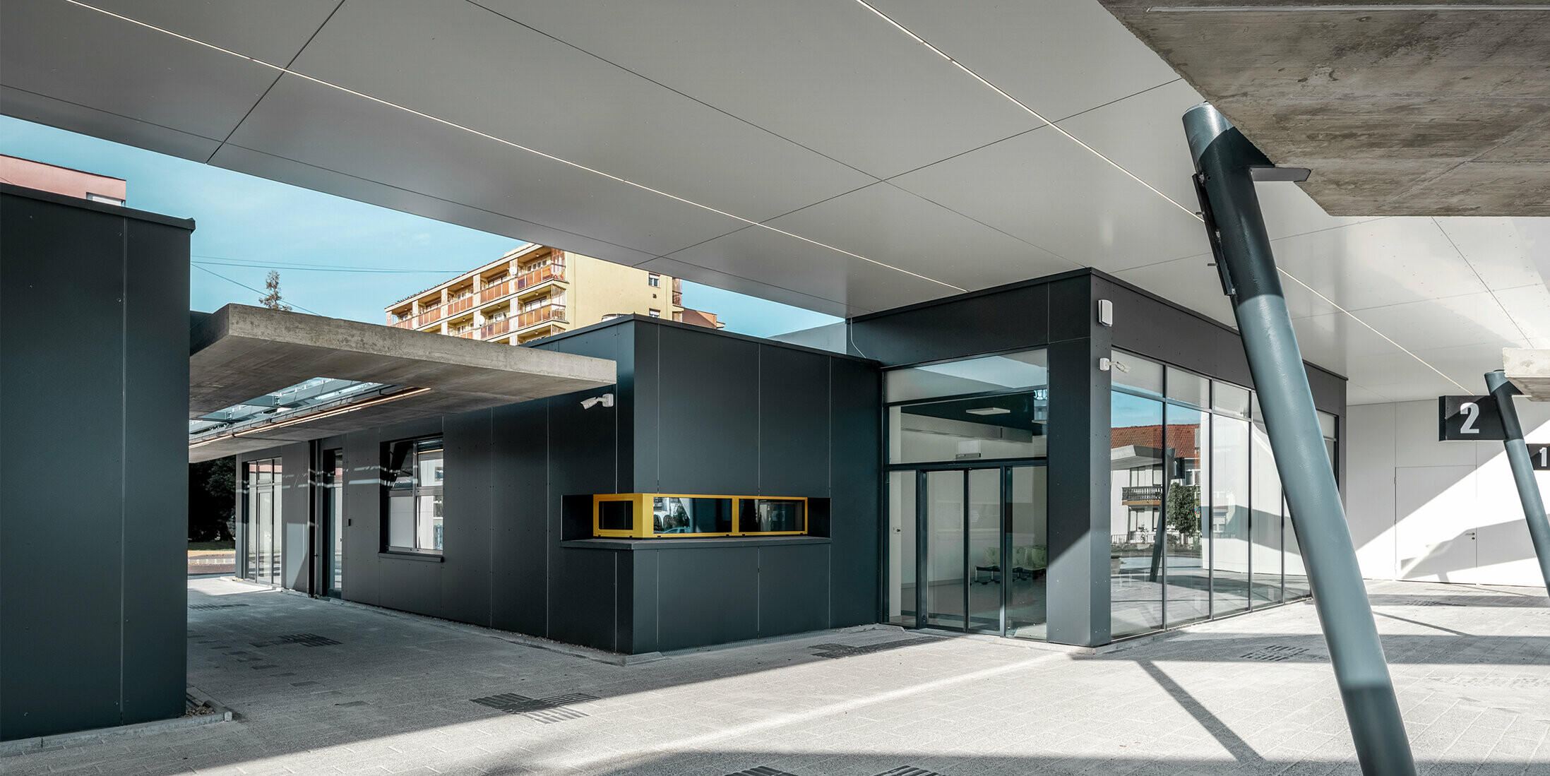 Überdachter Bereich des Busbahnhofs Lenti; Die Untersicht der Überdachung ist mit PREFABOND Verbundplatte in Reinweiß verkleidet, die Fassadenelemente beim Eingangsbereich in P.10 Anthrazit.