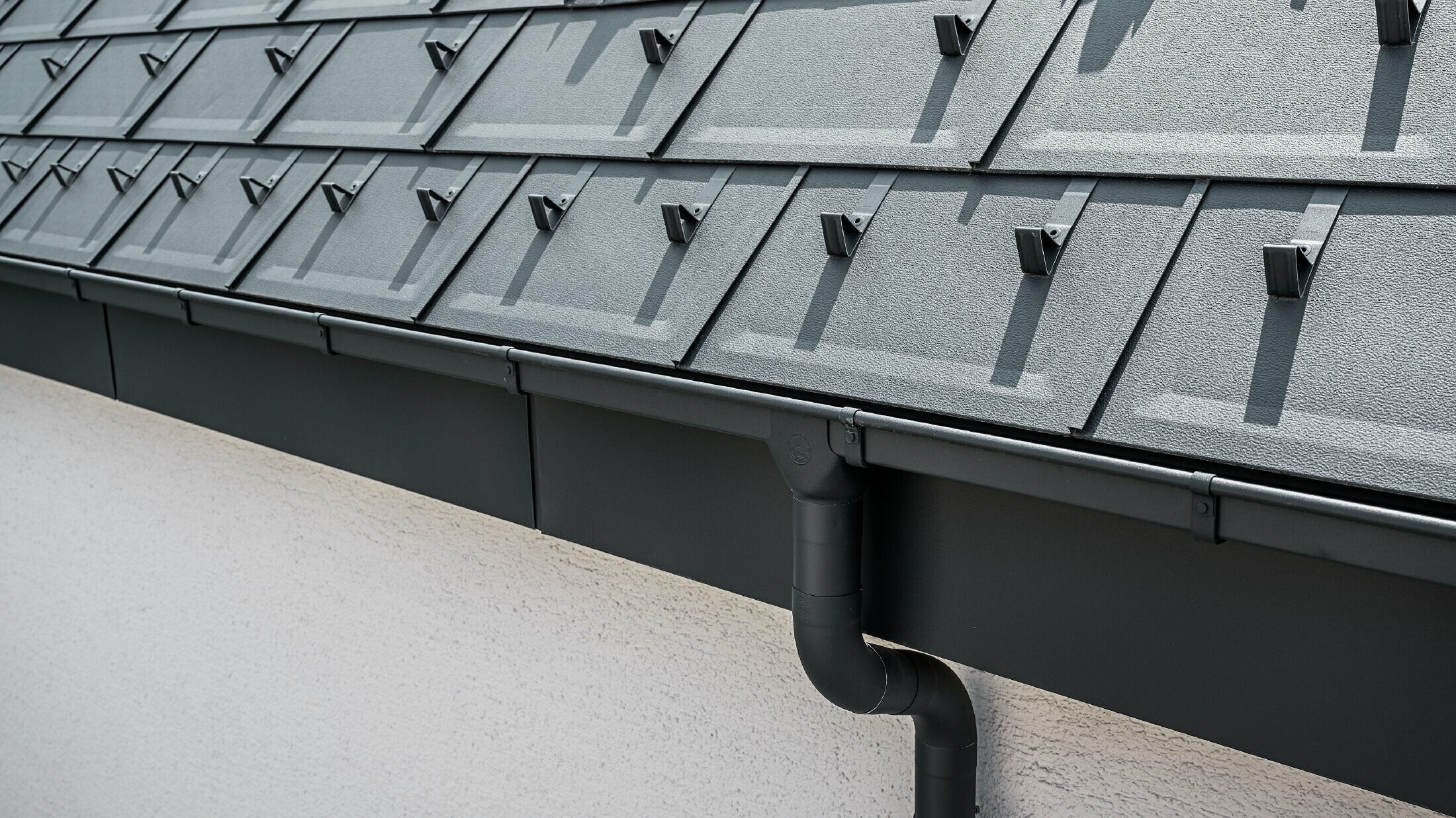 Superficie del tetto ripida coperta dal pannello di tegola R.16 con canale quadro PREFA con bacino di raccolta e tubo pluviale in antracite