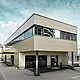 Moderner Zubau mit Werkstatt und Büro von Guggisberg Dachtechnik in Wabern (Schweiz). Die Gesamtansicht des Bürogebäudes betont die stilvolle PREFA Aluminiumfassade in Bronze. Die horizontal ausgerichtete Linienführung und das Flachdach unterstreichen die zeitgemäße Formensprache und die exklusive Materialwahl.
