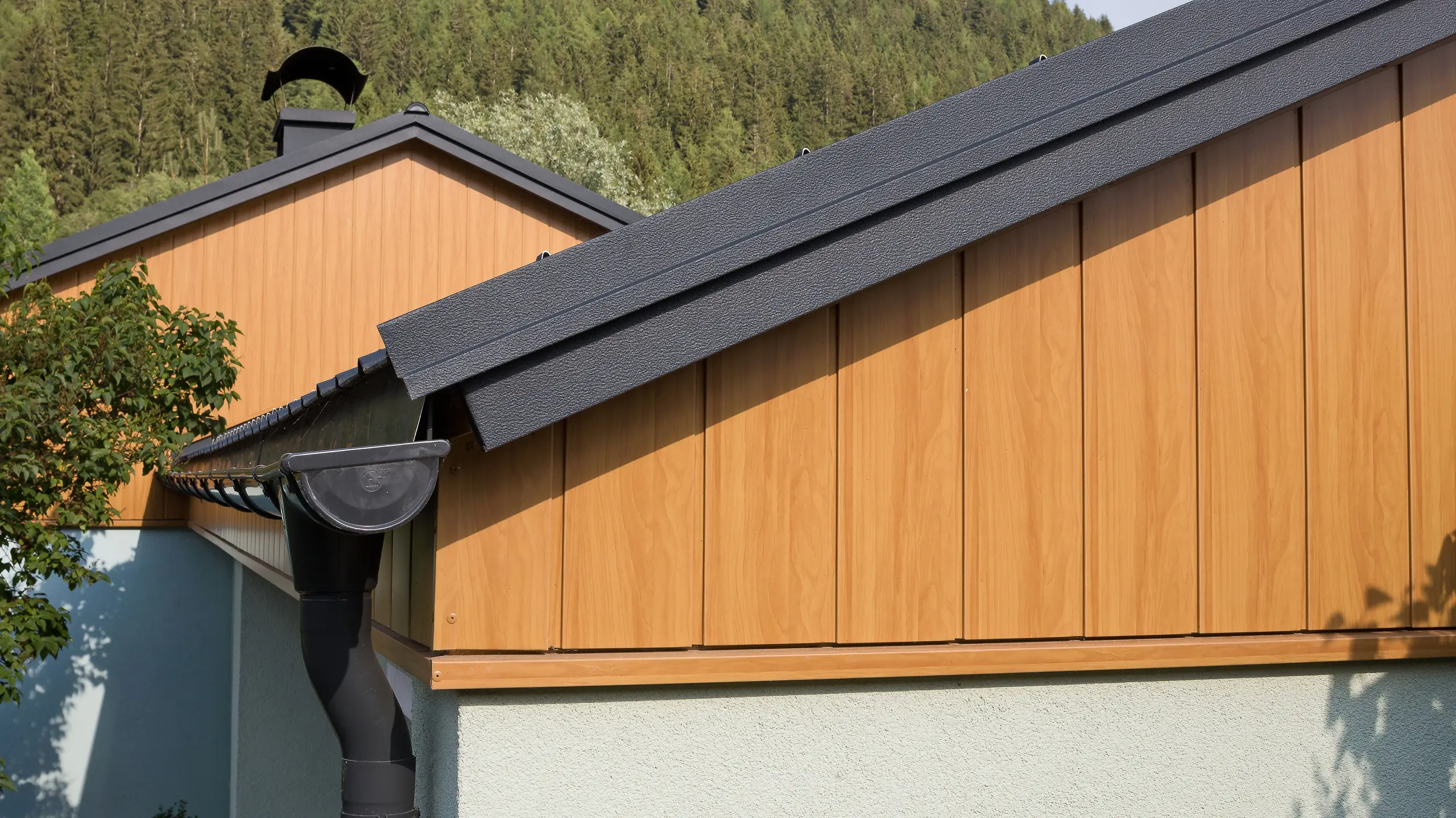 Giebelverkleidung mit den Alu Sidings von PREFA in Eiche natur senkrecht montiert mit einer PREFA Dachrinne in Anthrazit.