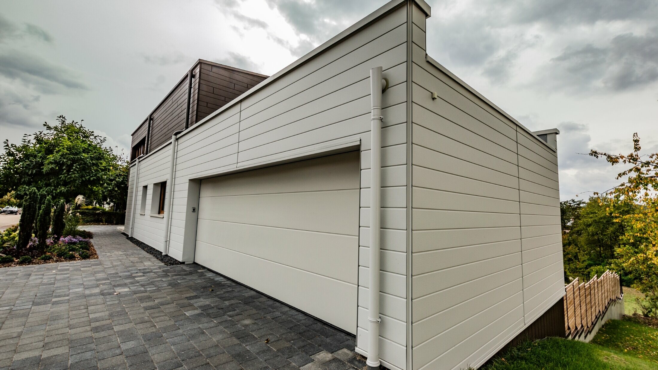 Rivestimento del garage con doga PREFA in bianco posata orizzontalmente con grondaia con sbocco PREFA.