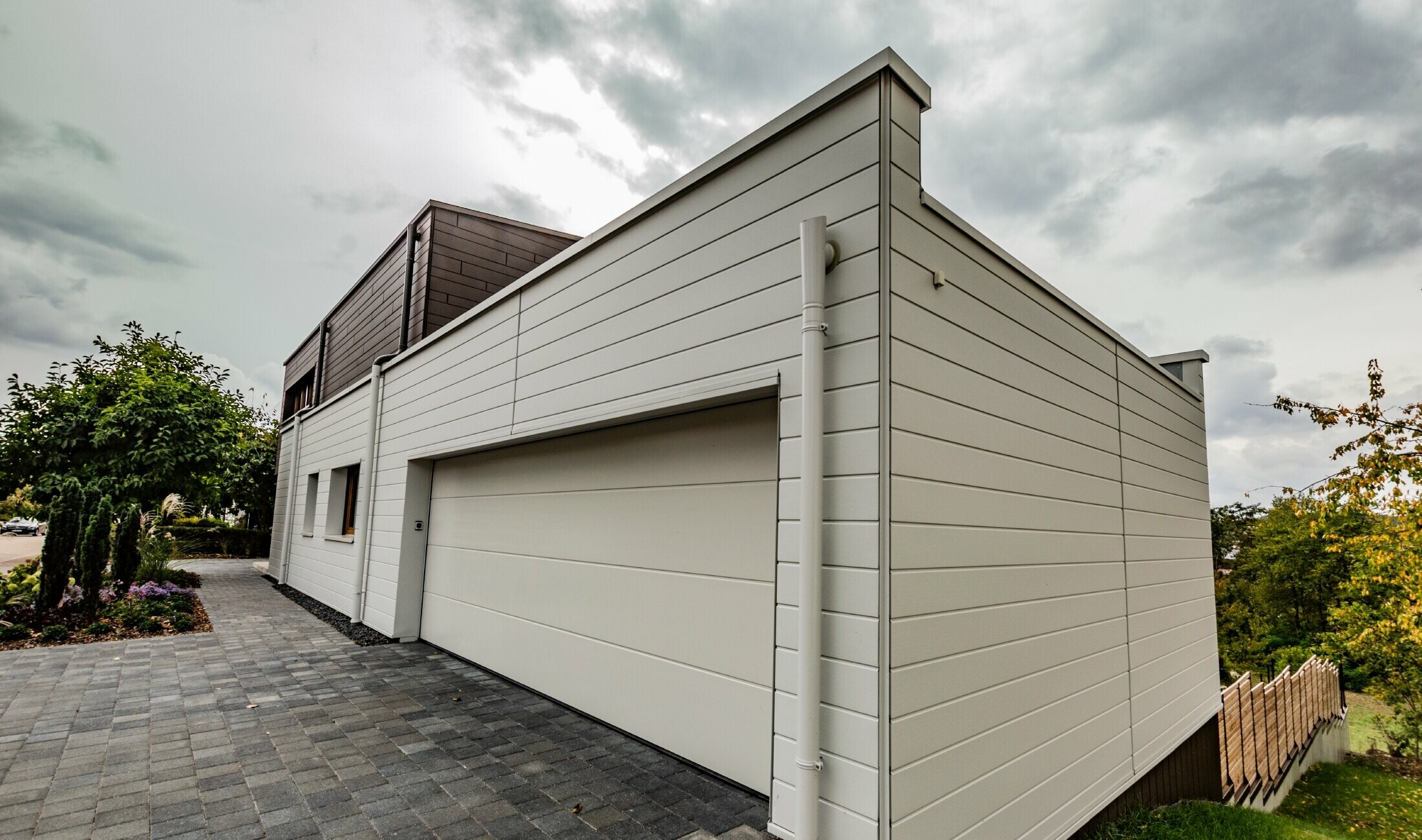 Rivestimento del garage con doga PREFA in bianco posata orizzontalmente con grondaia con sbocco PREFA.