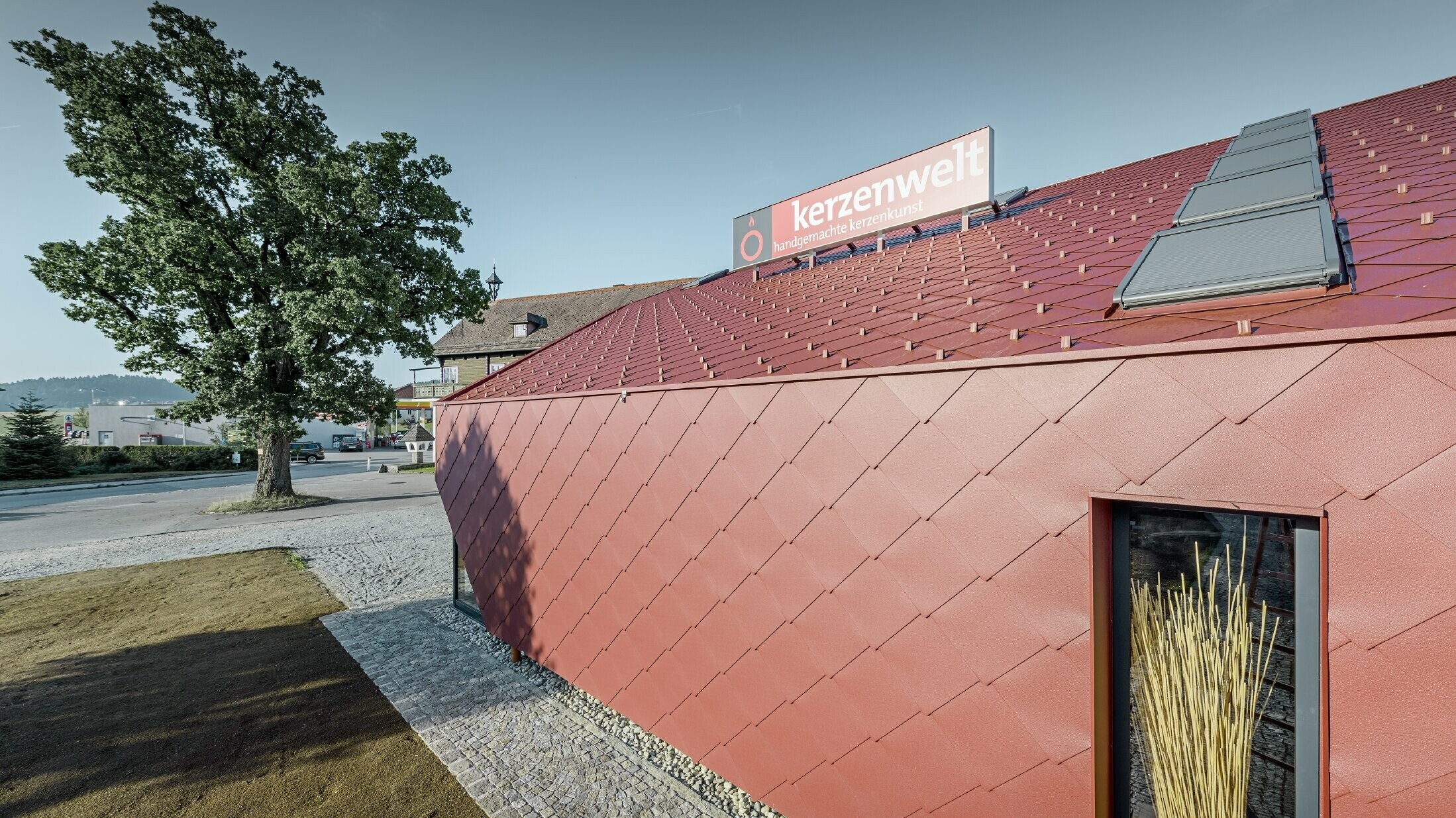 Il Kerzenwelt a Schlägl è stato completamente rivestito con la scaglia PREFA. La copertura e il rivestimento della facciata sono stati realizzati con scaglia 44 × 44 in rosso ossido.