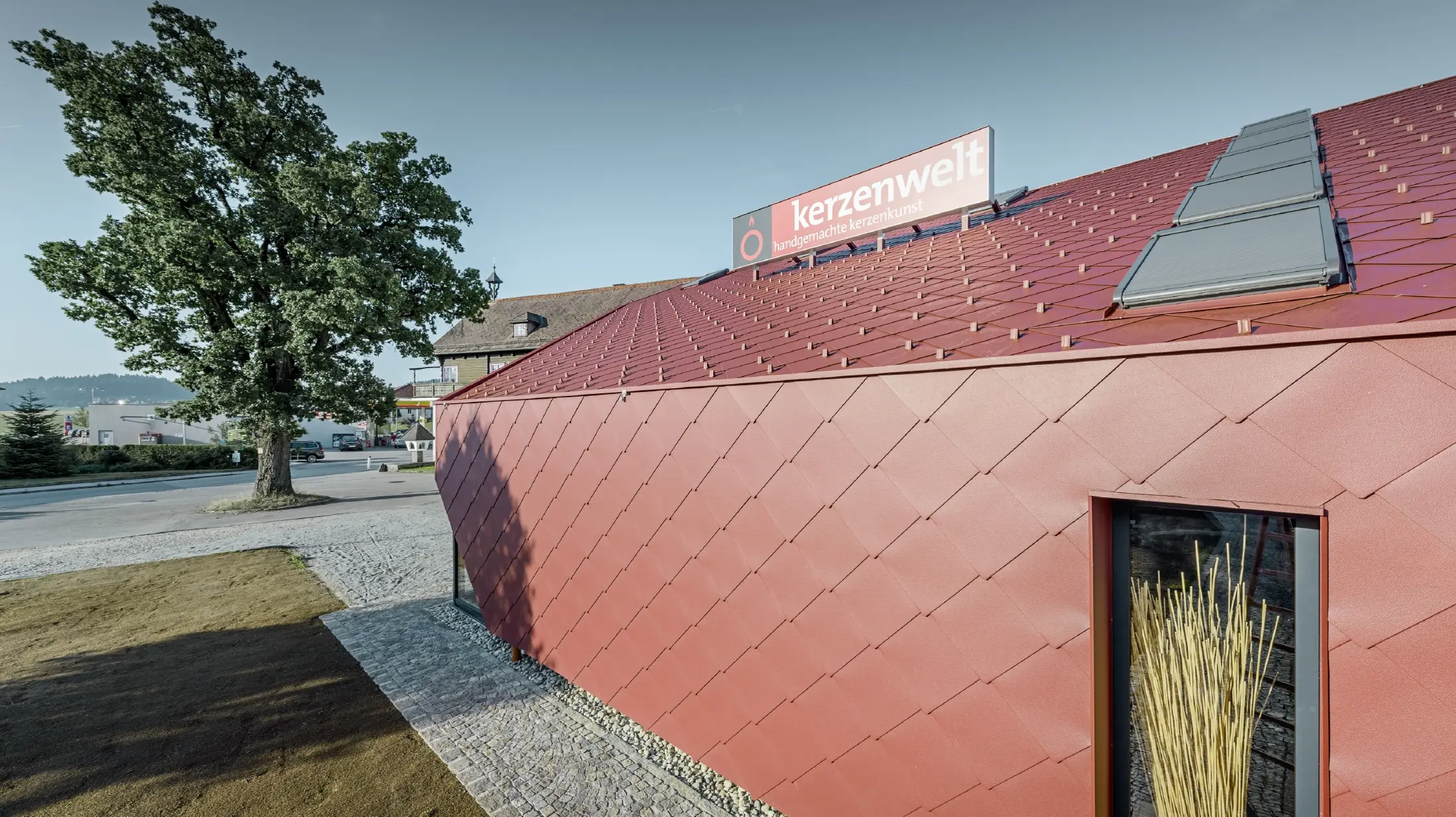 Il Kerzenwelt a Schlägl è stato completamente rivestito con la scaglia PREFA. La copertura e il rivestimento della facciata sono stati realizzati con scaglia 44 × 44 in rosso ossido.