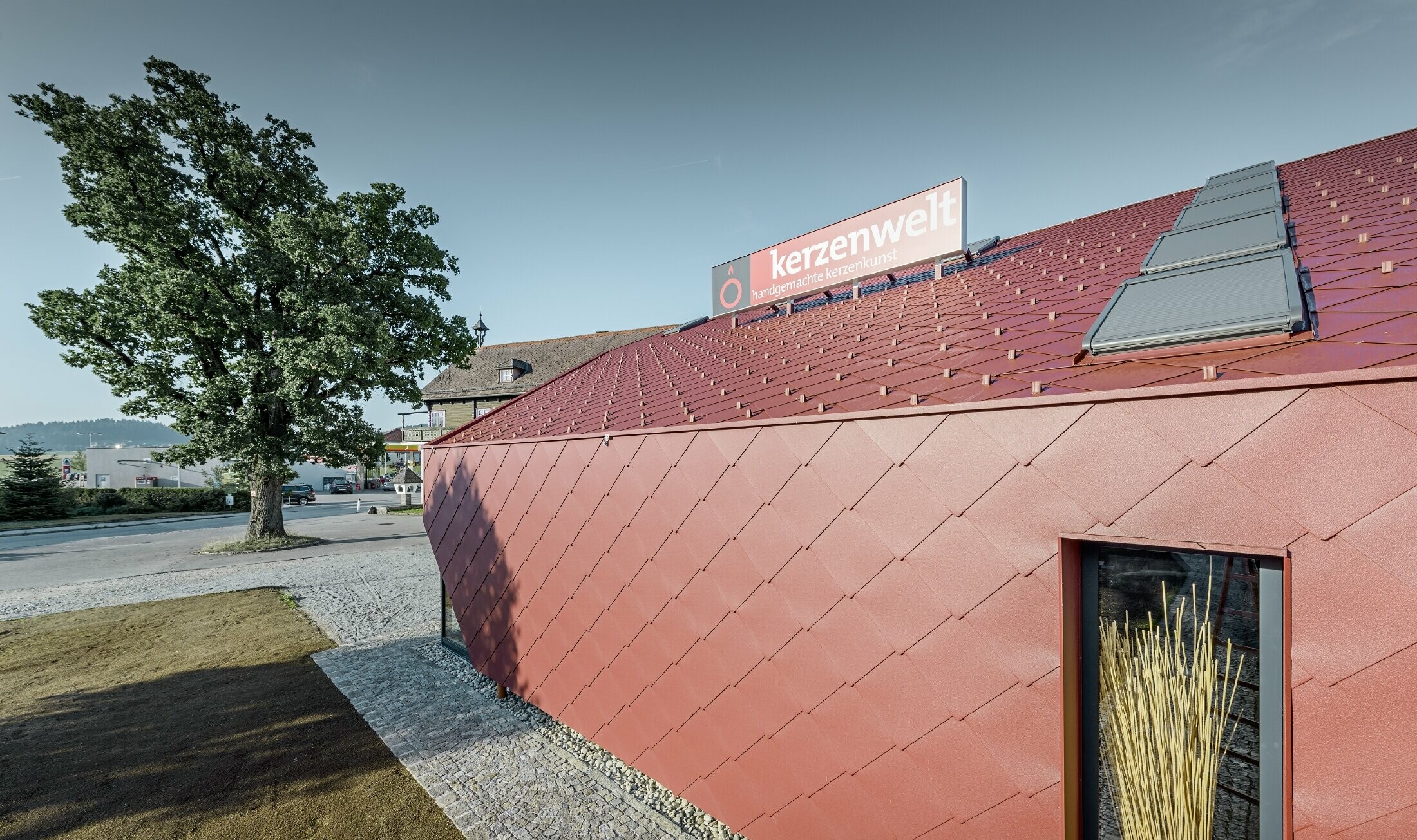 Il Kerzenwelt a Schlägl è stato completamente rivestito con la scaglia PREFA. La copertura e il rivestimento della facciata sono stati realizzati con scaglia 44 × 44 in rosso ossido.
