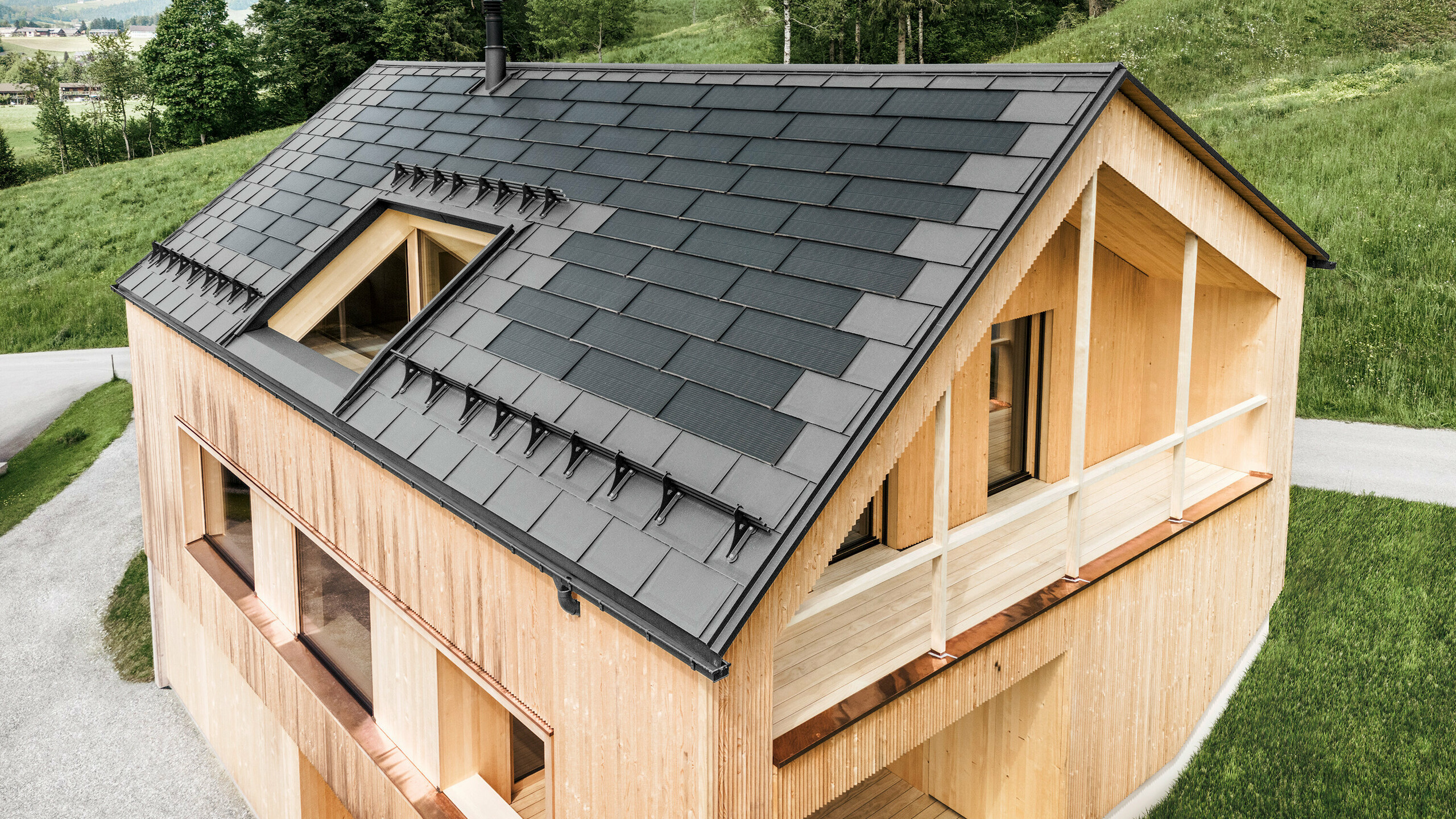 Einfamilienhaus im österreichischen Ort Egg mit der PREFA Solardachplatte und der Dachplatte R.16 in Hellgrau, kombiniert mit einer Holzfassade