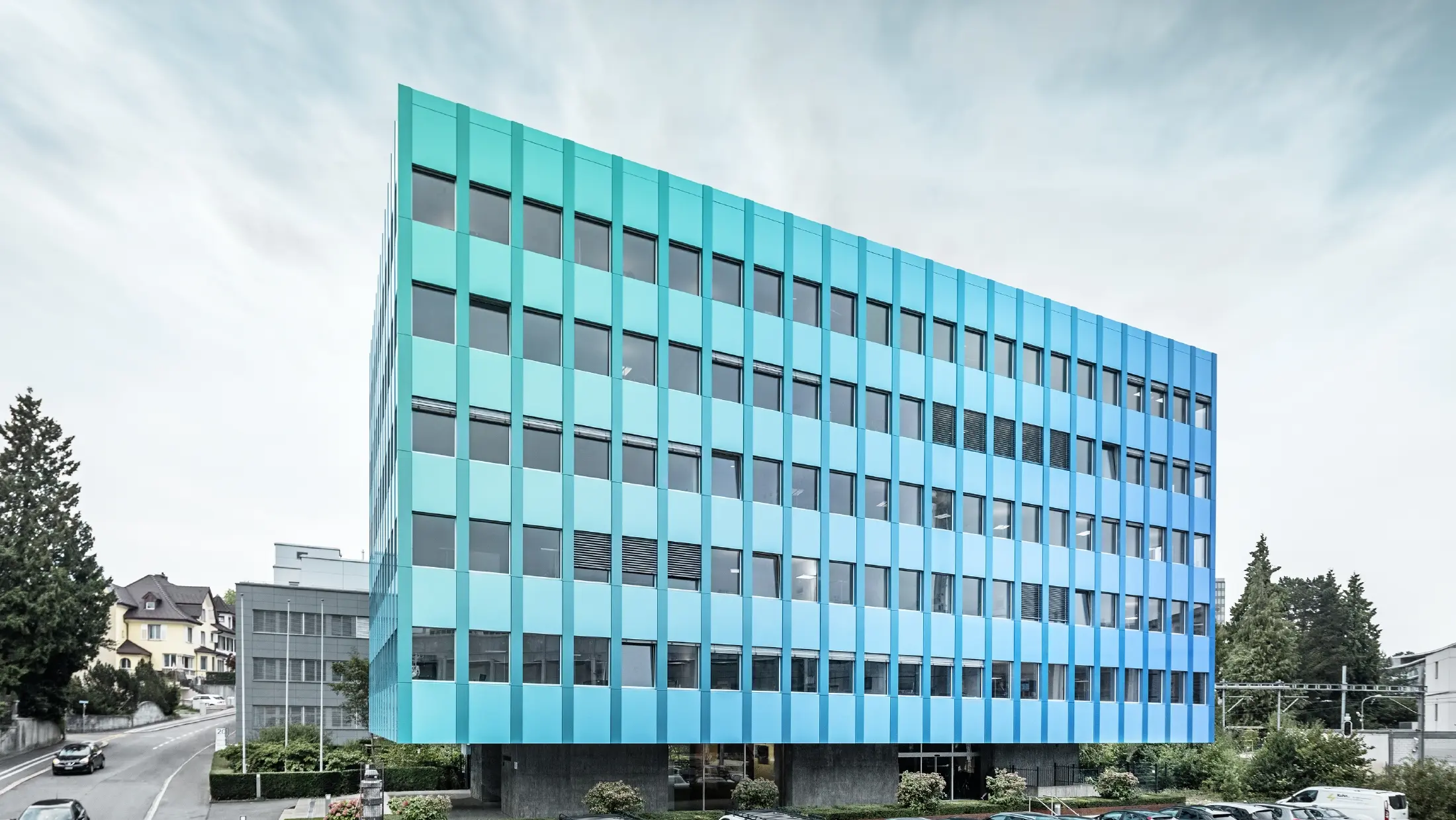 Vista laterale della Wielandhaus ad Aarau; la facciata è rivestita con pannelli compositi in alluminio PREFABOND di PREFA, che grazie allo speciale processo di rivestimento brillano di riflessi blu-verdi.