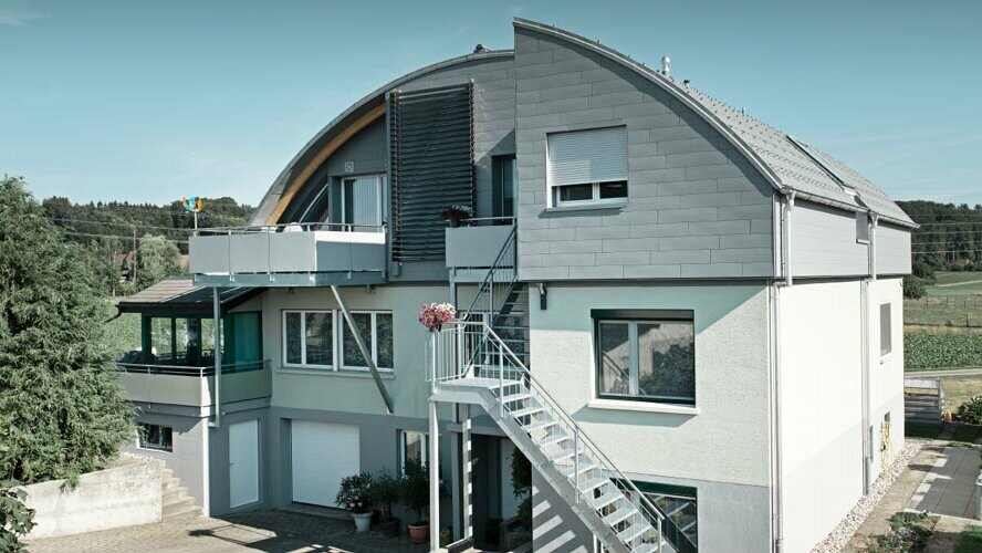 Casa privata con tetto a botte rivestito con tegole PREFA e Prefalz in P.10 grigio chiaro