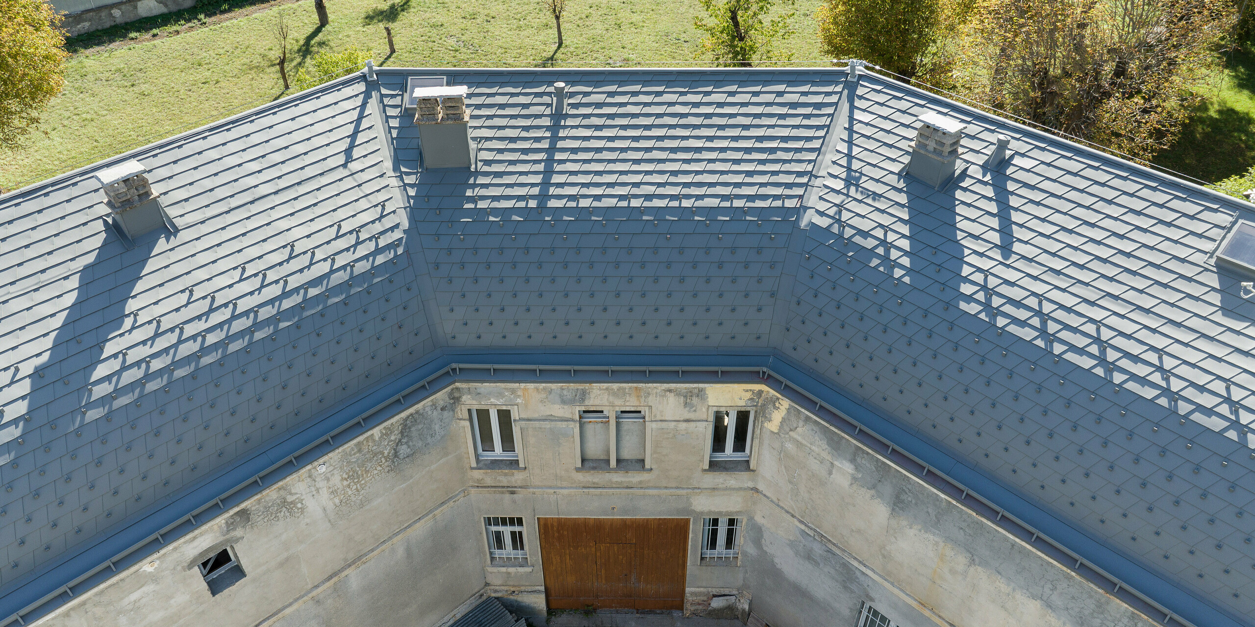 Die großflächige Dachlandschaft eines Anwesens in Barcelonnette, Frankreich wurde mit der PREFA Dachschindel in P.10 Hellgrau saniert. 