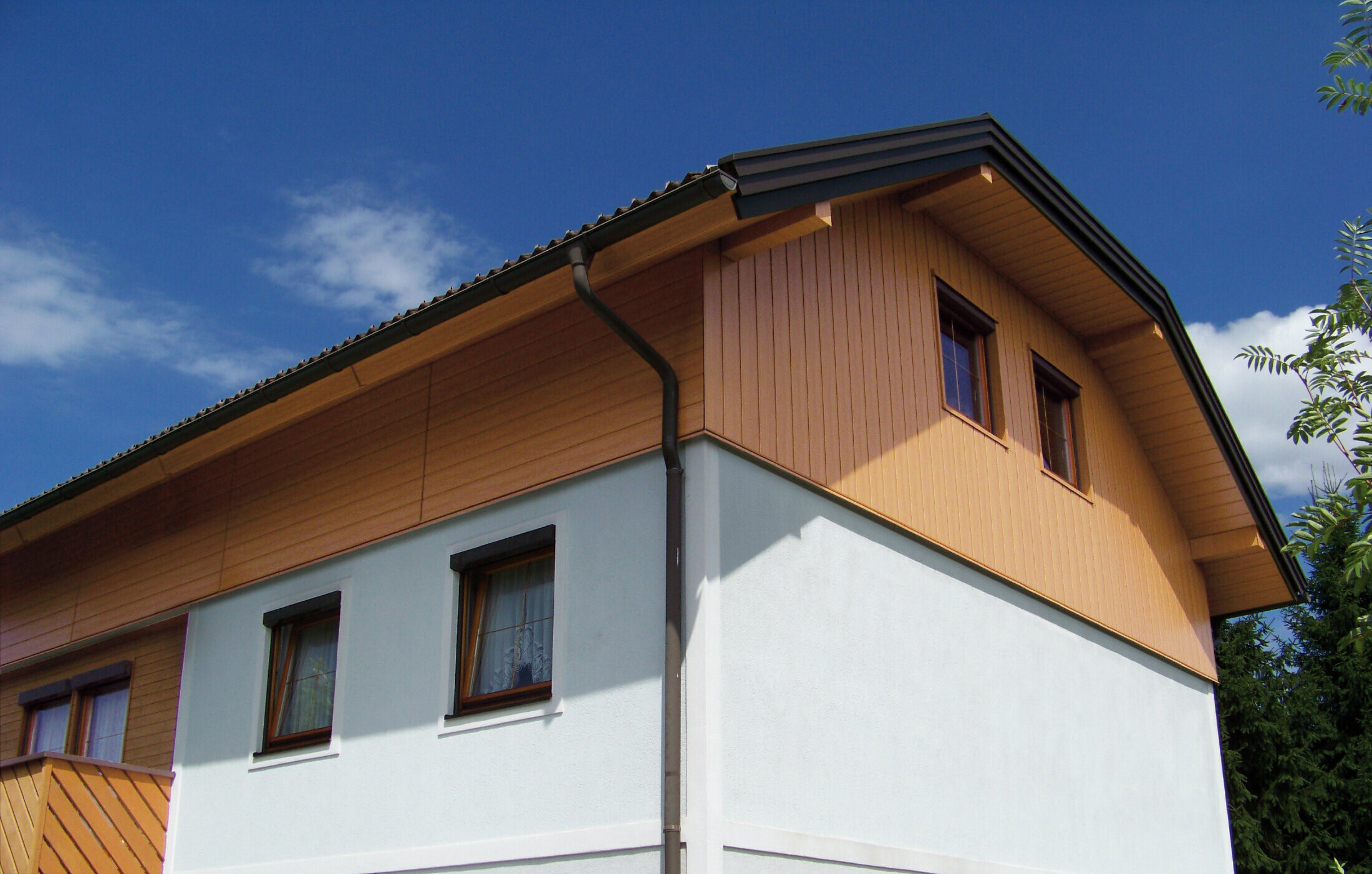 Großes Einfamilienhaus mit Krüppelwalmdach und einer Giebelverkleigung mit den PREFA Sidings in Holzoptik (Farbe Eiche natur)