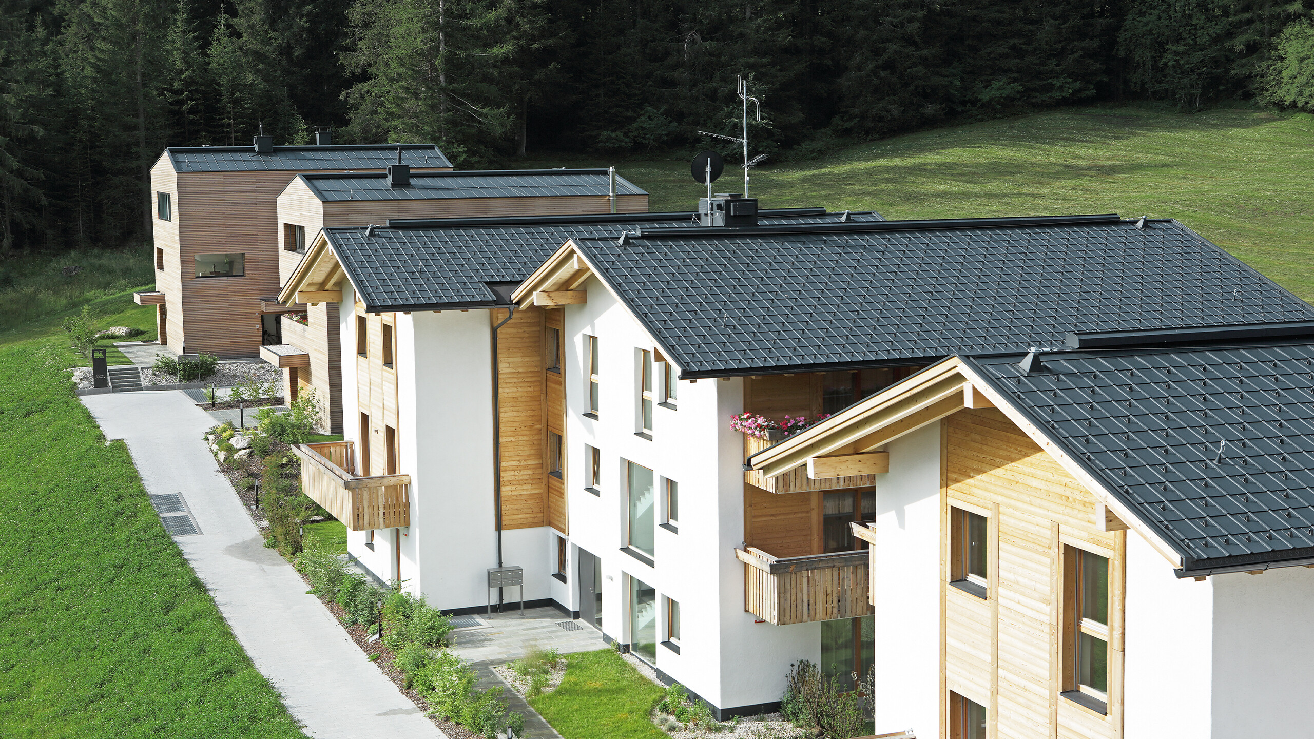 [Translate to Deutsch:] Aufnahme der fünf Wohnbauten in Corvara, eingedeckt mit der PREFA Dachplatte und Stehfalz in Anthrazit aus sturmsicherem Aluminium