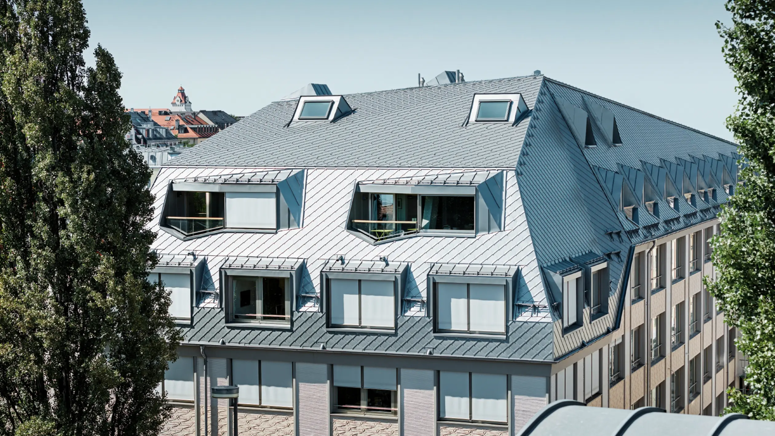 Dachausbau eines Walmdaches in derLeopoldstraße/Ecke Hohenzollernstraße in München. Viele Loggiaausschnitte und Fensterausschnitte werden von der PREFA Dachraute eingekleidet.