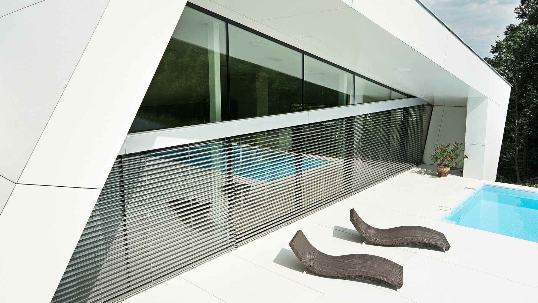 Modernes Einfamilienhaus mit Swimmingpool. Die Fassade des Gebäudes ist mit Verbundplatten in Reinweiß verkleidet.