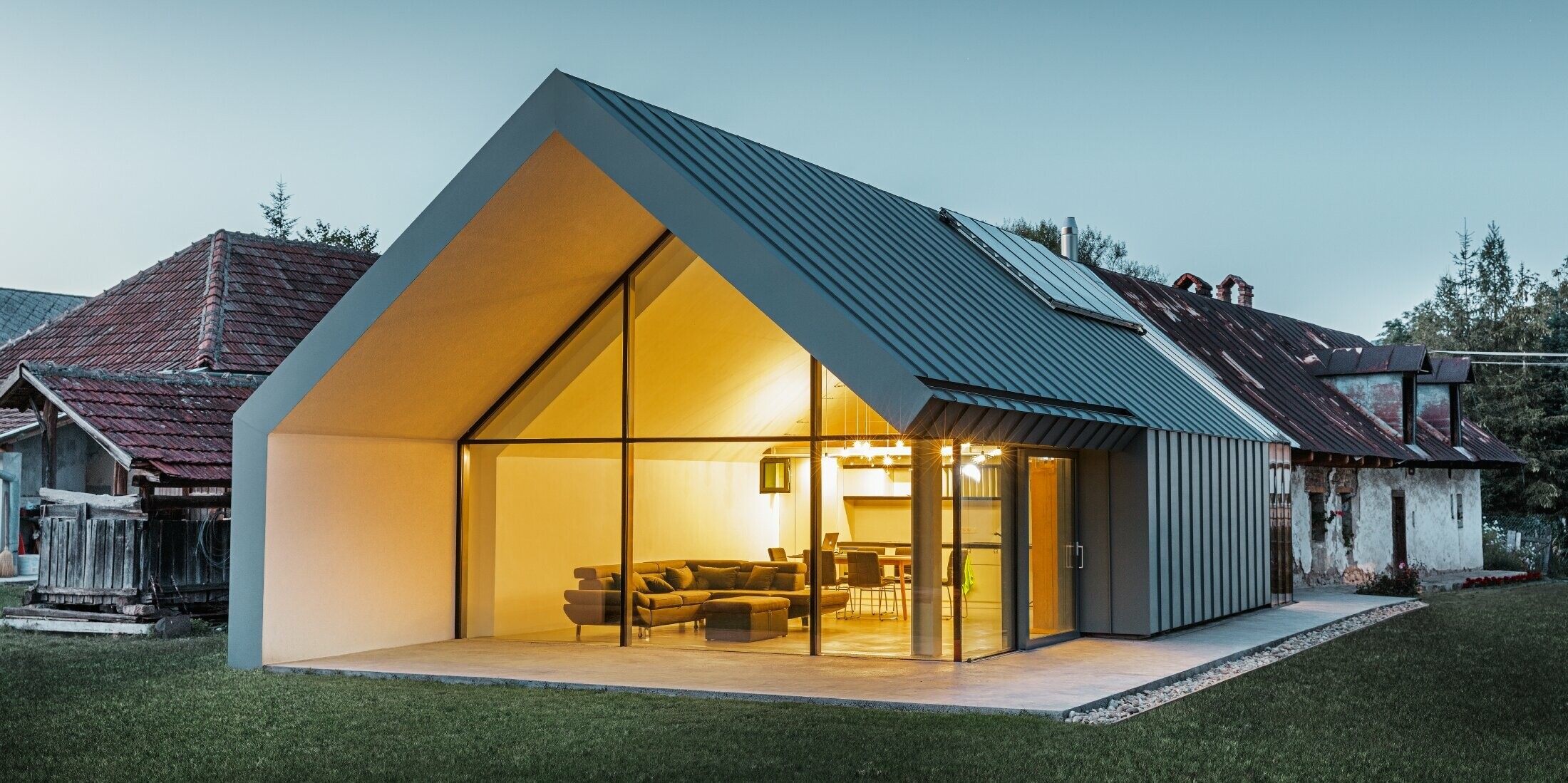 modernes neues Architektenbüro und Einfamilienhaus im Anschluss an ein altes Bauernhaus mit Steinfassade, verkleidet mit Stehfalz und Winkelstehfalz von PREFA in hellgrau