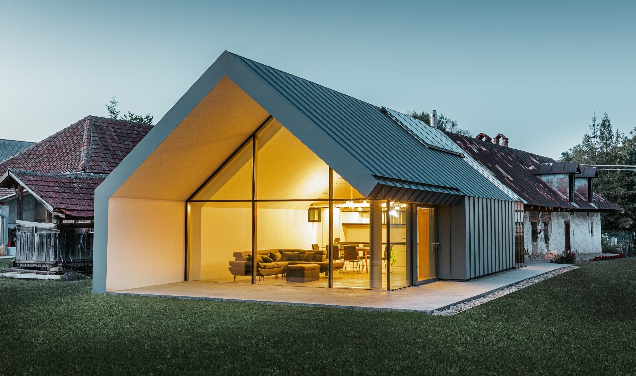 modernes neues Architektenbüro und Einfamilienhaus im Anschluss an ein altes Bauernhaus mit Steinfassade, verkleidet mit Stehfalz und Winkelstehfalz von PREFA in hellgrau