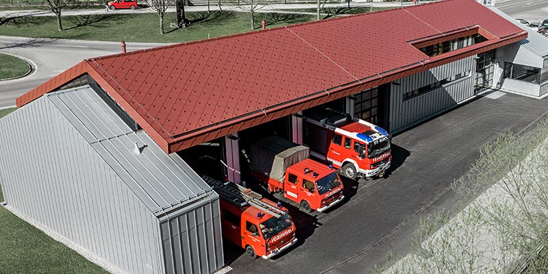 Feuerwehrhaus der Firma PREFA in Marktl mit rotem Rautendach und Stehfalzdach und -fassade in Silbermetallic. Mehr Infos zu den Brandklassen erhalten Sie hier.