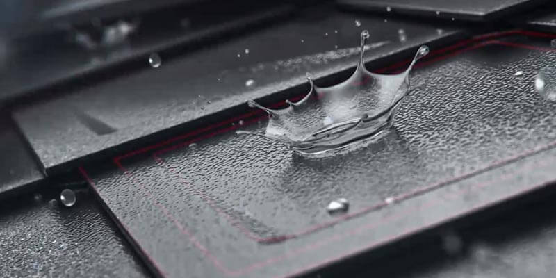 Zoom sulla scaglia PREFA con gocce d'acqua sulla superficie. La superficie della tegola è a stucco, il colore è antracite. 